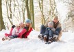 Family Sledging Through Snowy Woodland