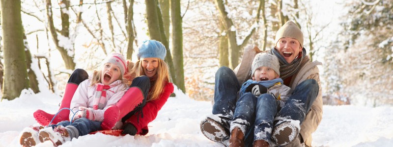 Family Sledging Through Snowy Woodland